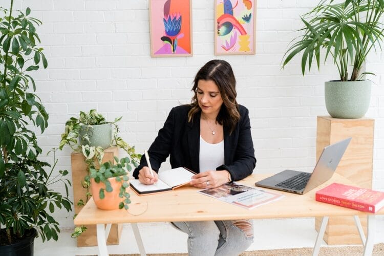 TCS Member Panayiota Ward sits at the desk of her celebrant business making notes