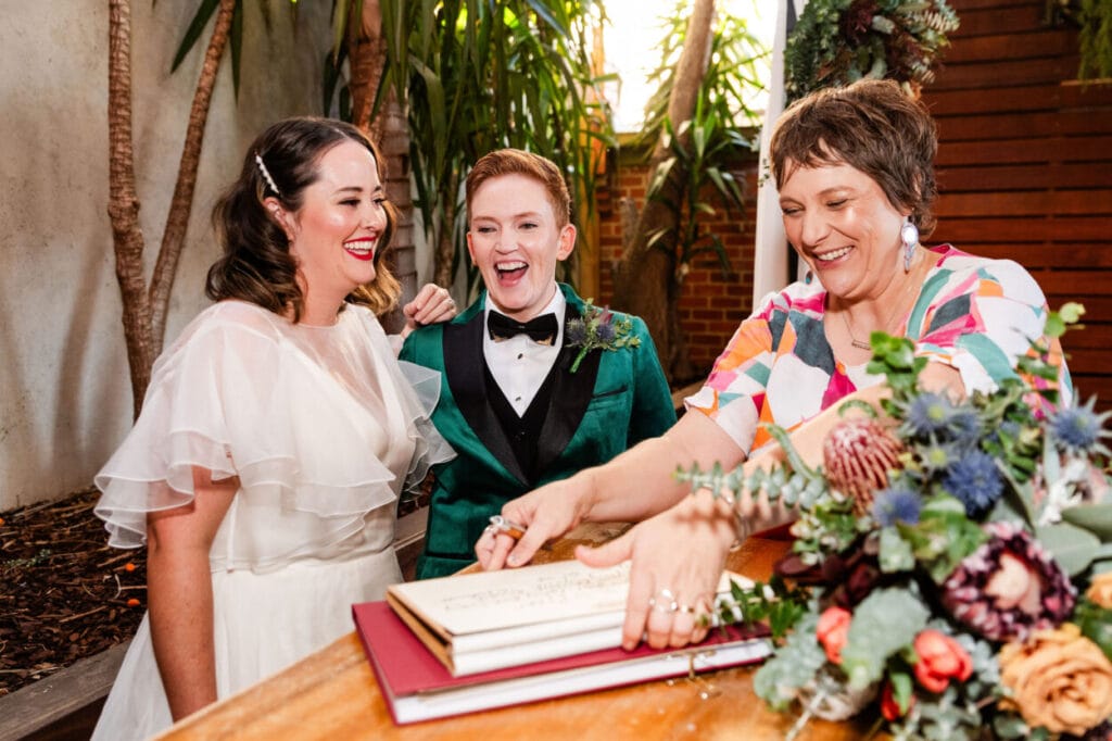 Couple at LGBTIQA+ wedding signing paperwork with Melbourne celebrant Dee Wild