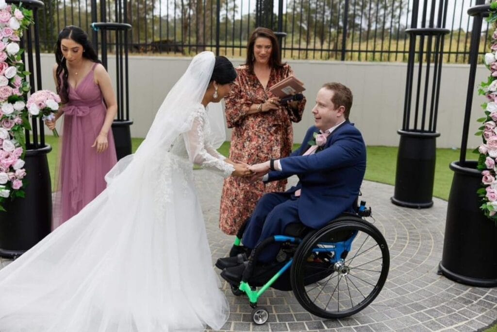 Sydney celebrant Jo Booth marrying a laughing couple. The groom is in a wheelchair