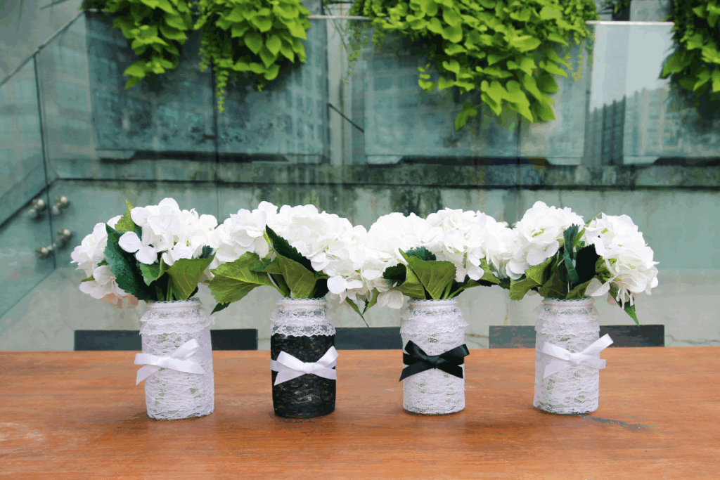 Flowers in mason jars decorated with black and white lace