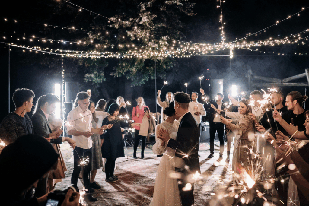 Guests hold sparklers while bride and groom have their first dance