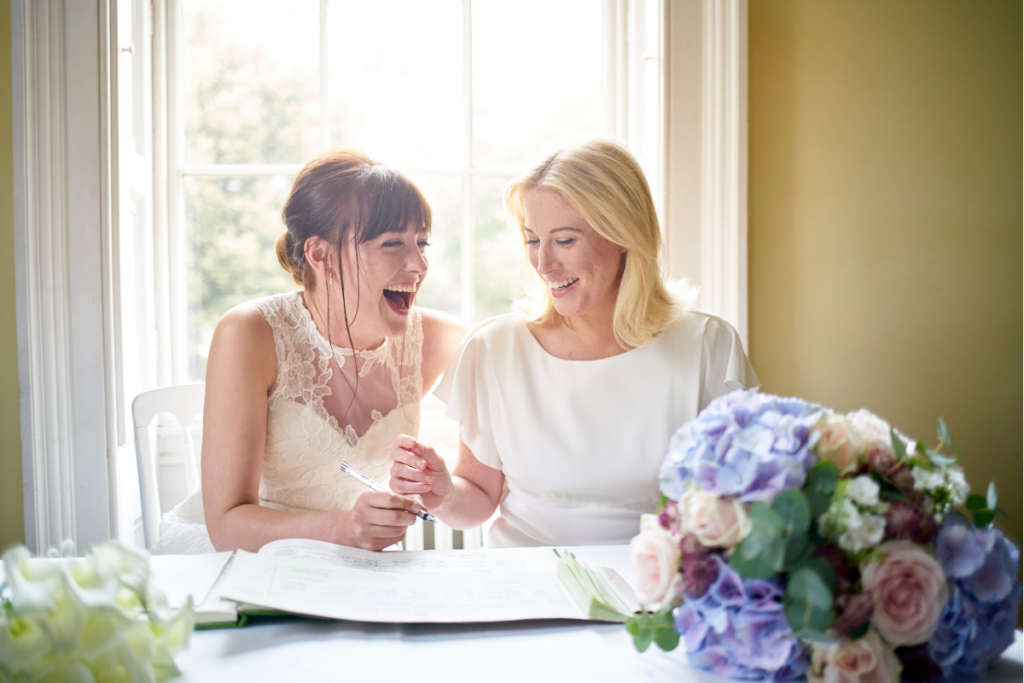 Two brides signing the wedding registry. They are laughing together