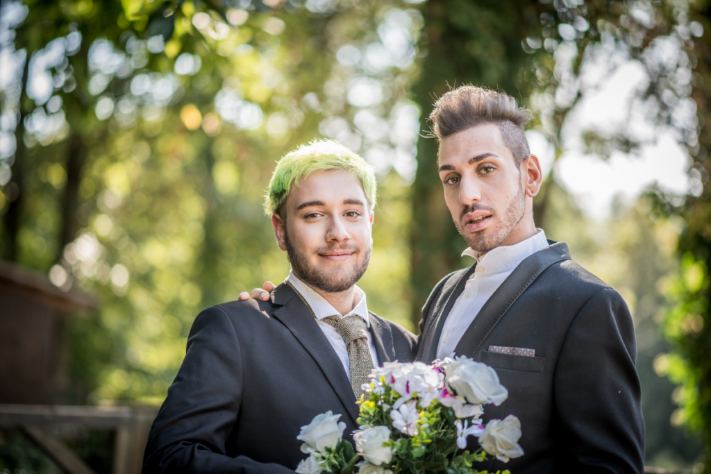 two Gen Z grooms on their wedding day. One has green hair and the other has a fauxhawk