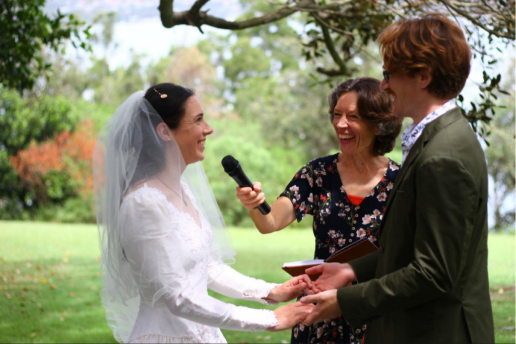 Kathryn Iles is a celebrant and teacher based on Sydney's Northern Beaches. She is holding the microphone for two people getting married and saying their vows