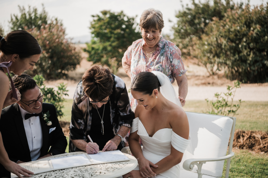NSW celebrant Tanaye Quinn at the signing table during a wedding with the bride, groom and their two mothers as witnesses