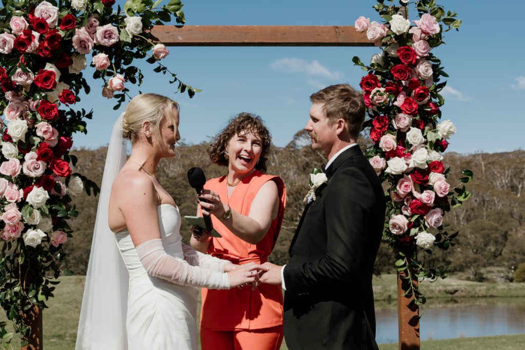 Upper Murray Celebrant Yolande Szery smiling while holding the microphone for the bride and groom in during their wedding